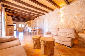 A spacious living area with a stone wall, wooden beams, and a beige sofa.