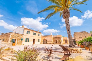 A traditional stone building with a courtyard, palm tree, and rustic outdoor furniture.