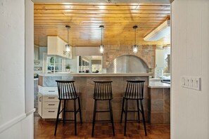 A kitchen with a stone arch, wooden ceiling, and three bar stools. - Mountain Fun Lodge: Big Spaces, Big Views, Endless Games, Family Memories (Running Springs)