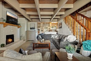 A living room with a fireplace, a sofa set, a coffee table, and a staircase. - Mountain Fun Lodge: Big Spaces, Big Views, Endless Games, Family Memories (Running Springs)