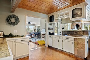 A kitchen with white cabinets, a wooden ceiling, and a stone backsplash. - Mountain Fun Lodge: Big Spaces, Big Views, Endless Games, Family Memories (Running Springs)
