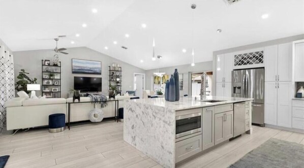 A modern kitchen with a marble island, stainless steel appliances, and a large dining area.