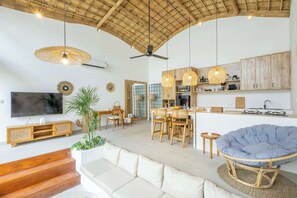 A spacious living area with a high ceiling, wooden ceiling, and a large TV on the wall. - Casa Viorica (Canggu)