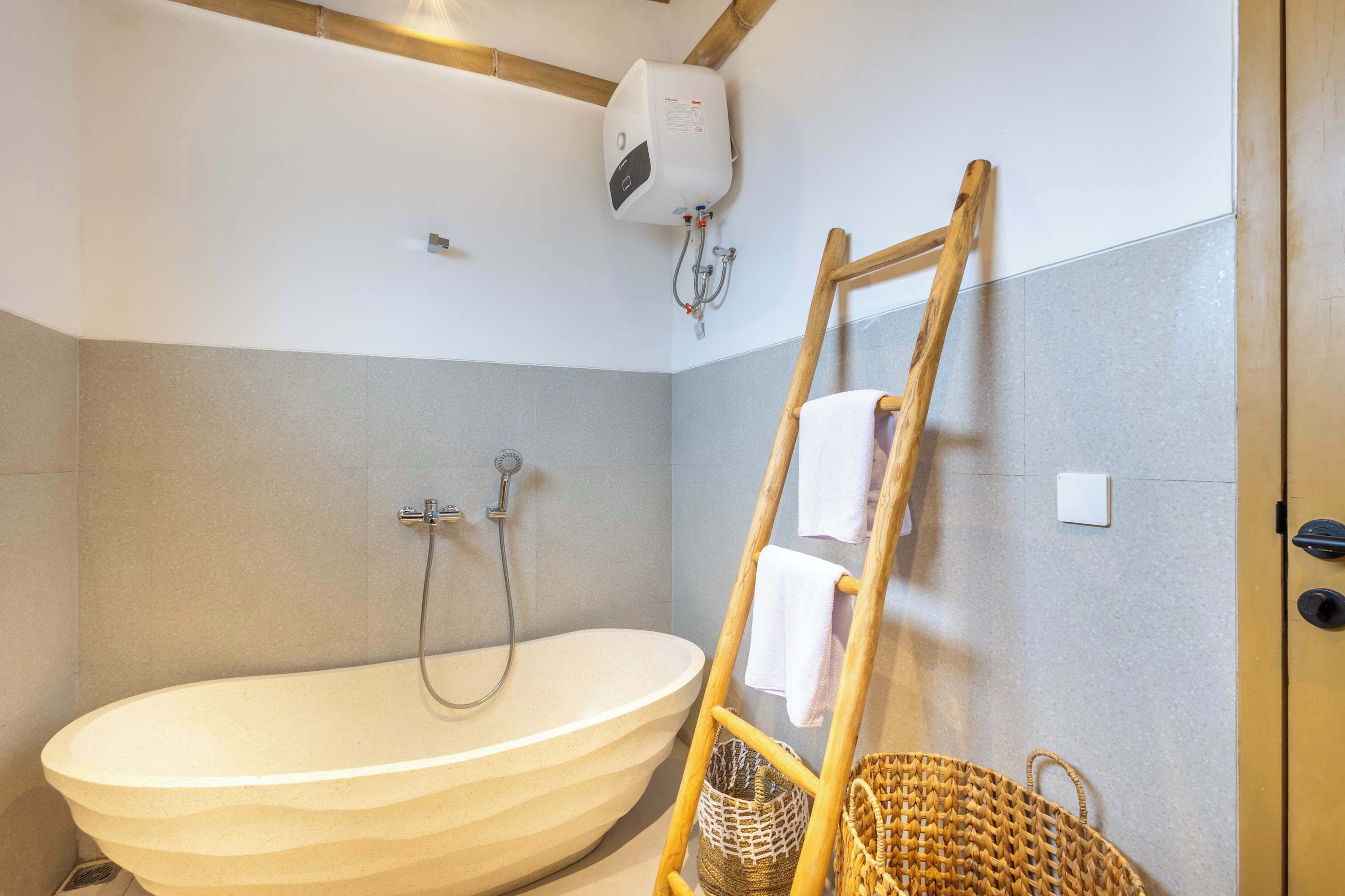 Een badkamer met een vrijstaand bad, een douche, een handdoekrek en een houten ladder.
