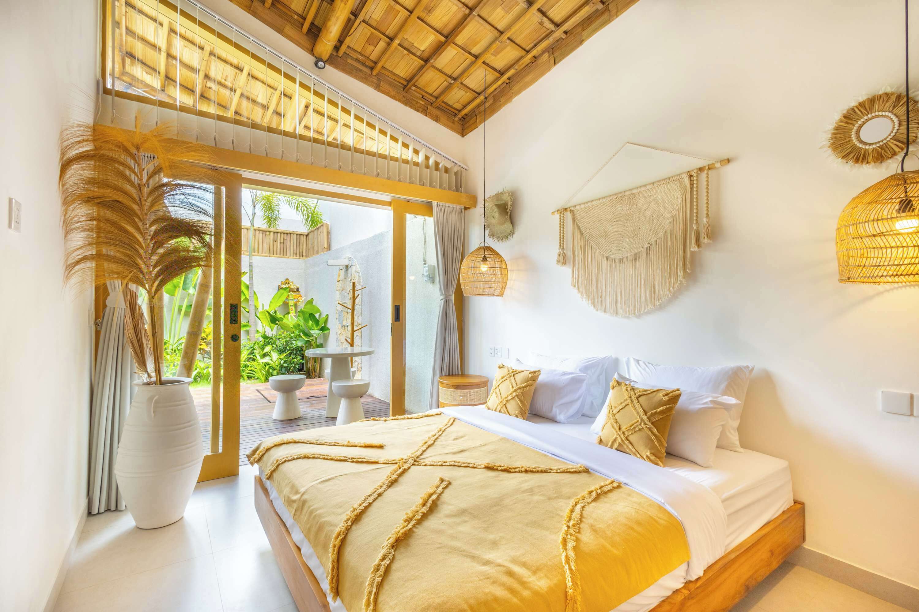 A bedroom with a bed, a large window, and a view of greenery outside.