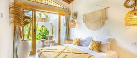 A bedroom with a bed, a large window, and a view of greenery outside.