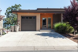 A modern building with a garage door, a small entrance, and a concrete driveway. - Clearwater Summit: Panoramic Gorge Views & Modern Design (Hood River)