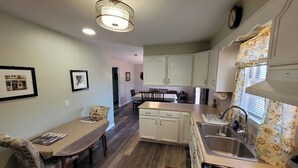 A kitchen with a stove, sink, and dining area with chairs and a table. - 3-bedroom house in Deale located on Bay  many amenities and great views (Deale)