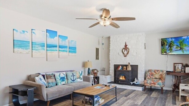 A living room with a sofa, coffee table, fireplace, and artwork on the wall. - 3-bedroom house in Deale located on Bay  many amenities and great views (Deale)