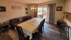 A dining area with a table, chairs, a chandelier, and a view through a window. - 3-bedroom house in Deale located on Bay  many amenities and great views (Deale)