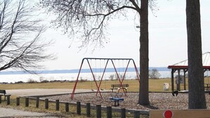 A park with swings, a bench, and a view of a body of water. - 3-bedroom house in Deale located on Bay  many amenities and great views (Deale)