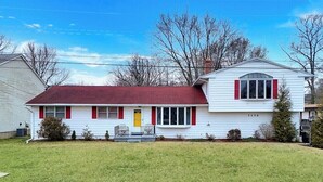 A two-story house with a red roof, white siding, and red shutters. - 3-bedroom house in Deale located on Bay  many amenities and great views (Deale)