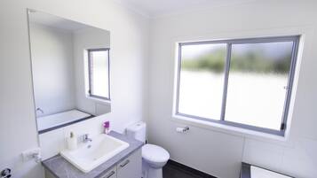 Ein Badezimmer mit Waschbecken, Spiegel, Toilette und Fenster.