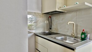 Een moderne keuken met een roestvrijstalen spoelbak, een ingebouwde kookplaat en een raam met uitzicht op een stadsgezicht.
