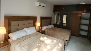 Ett hotellrum med två sängar, en garderob, en spegel och en luftkonditioneringsanläggning.