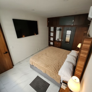 A bedroom with a bed, a TV mounted on the wall, a mirror, and a bedside lamp. - REFUGIO HOUSE Tlaquepaque historic center a/c (Guadalajara)