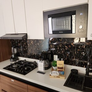 A modern kitchen with a black and gold backsplash, a built-in microwave, a gas stove, a coffee maker, and a coffee bag. - REFUGIO HOUSE Tlaquepaque historic center a/c (Guadalajara)