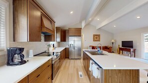 Eine moderne Küche mit Holzschränken, einem Edelstahlkühlschrank und einer großen Kücheninsel mit Spüle.