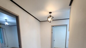Et værelse med trægulv, en loftlampe og en dør, der fører til et andet rum.