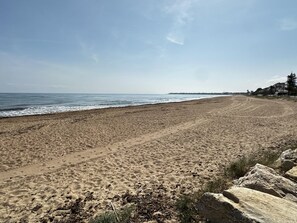 Ein weiter Sandstrand mit freiem Blick auf das Meer und einer fernen Küste.