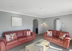 A modern living room with two leather sofas, a coffee table, and a framed picture on the wall.