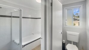 A bathroom with a shower, toilet, and a window. - Family 3-Bed Retreat Near Batehaven Beach (Batehaven)