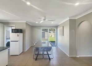 A kitchen with a refrigerator, microwave, and dining table with chairs.