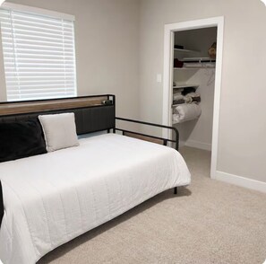 A bedroom with a bed, a closet, and a window with blinds. - Luxury Living  (Pattison)