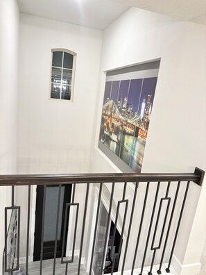 Eine Treppe mit Geländer, ein Fenster mit Blick auf die Stadt und eine Tür am unteren Ende.