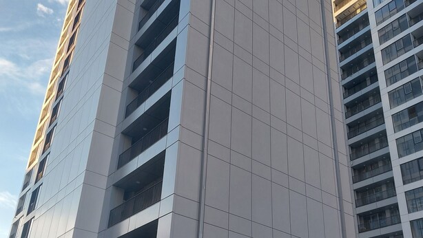 Un moderno edificio de gran altura con fachada de entramado, grandes ventanales y una entrada destacada.
