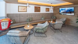 A modern lounge area with a sofa, chairs, a TV, and a vintage car. - Dreamy apartment right by the slope (Hinterglemm)