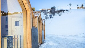 A wooden building with large windows, a snow-covered slope, and a ski lift in the background. - Dreamy apartment right by the slope (Hinterglemm)
