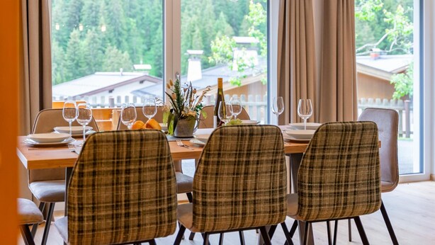 A dining area with a table set for four, chairs, a vase with flowers, and a bottle of wine. - Dreamy apartment right by the slope (Hinterglemm)