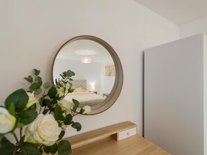Ein Schlafzimmer mit einem Bett, einem Nachttisch und einem Spiegel an der Wand.