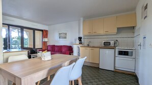 Eine kleine Küche mit Essbereich, einem roten Sofa und einem Fenster mit Vorhängen.