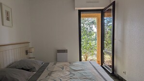 Ein Schlafzimmer mit Bett, Fenster, Wandklimaanlage und einem gerahmten Bild.