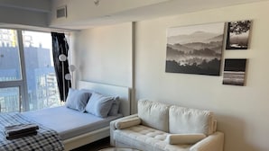 Ein Schlafzimmer mit einem Bett, einem Schlafsofa, einem Glastisch und Bildern an der Wand.