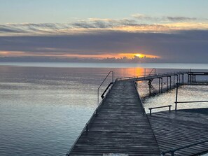A wooden pier extending into calm water with a sunset in the background. - 4 Star Holiday Home in Vaeggerlose (Vaeggerlose)