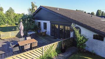 A residential property with a deck, outdoor seating, and a garden area.