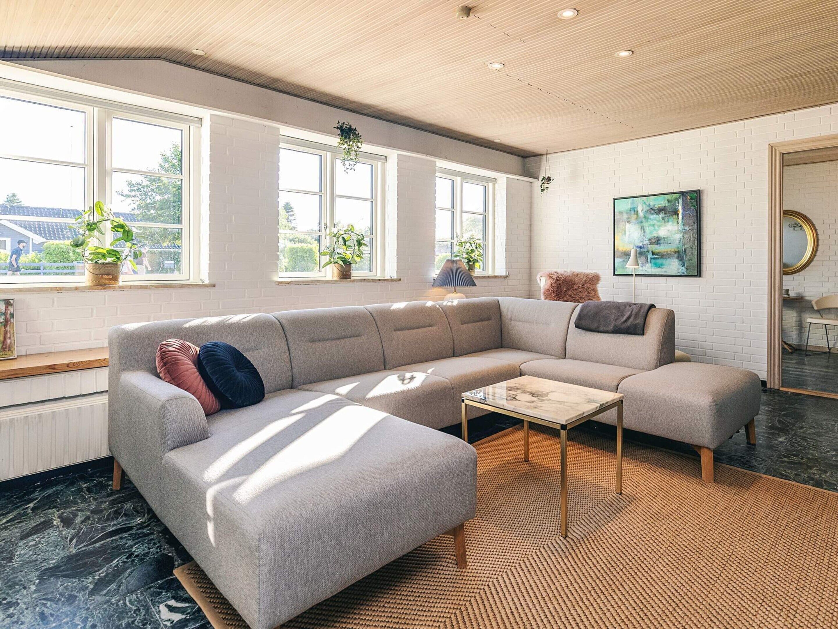 A modern living room with a sectional sofa, a coffee table, and a large window with plants.