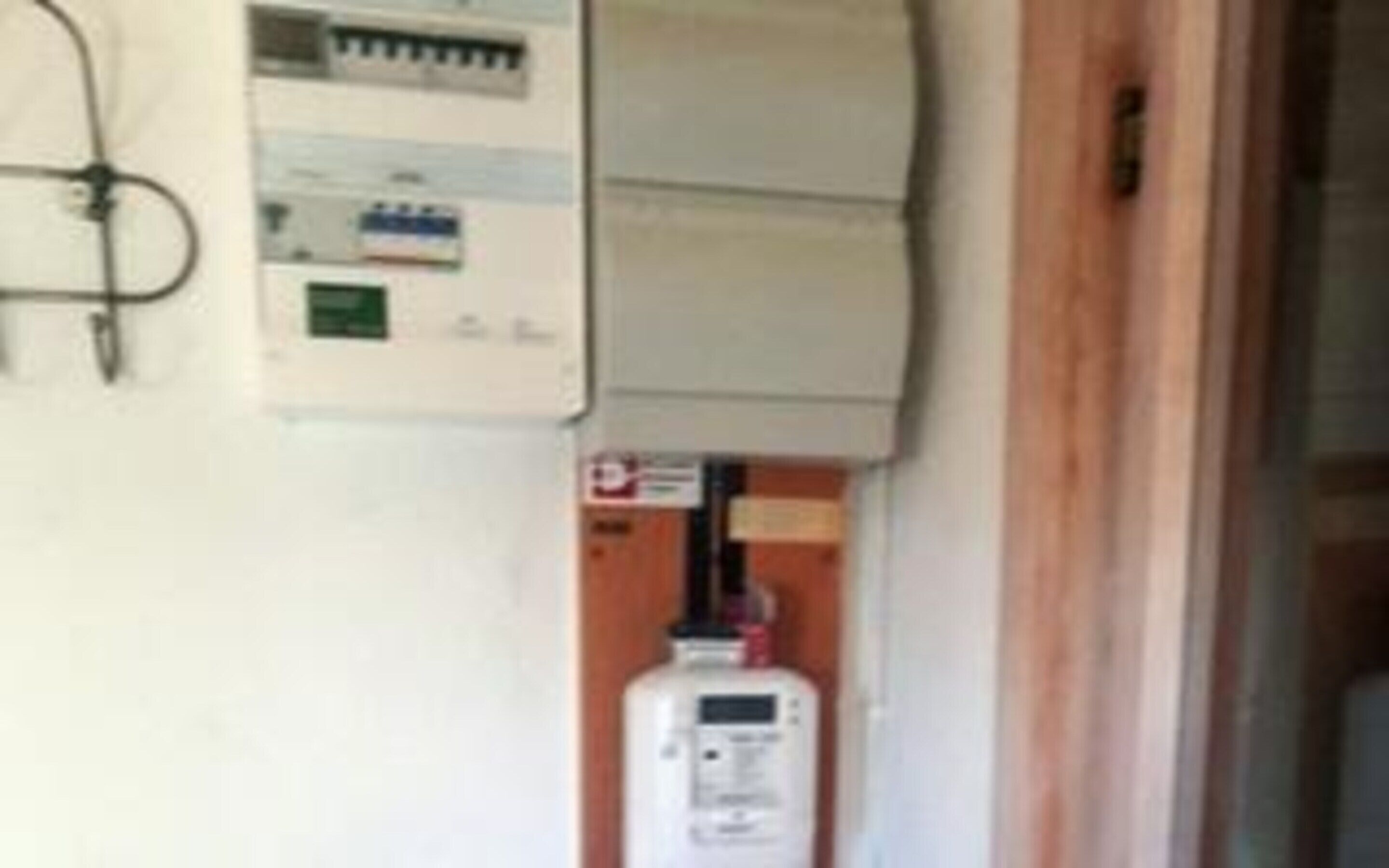 A utility meter and a white electrical panel on a wall.