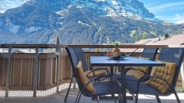 Ein Balkon mit Tisch und Stühlen mit Blick auf einen Berg.