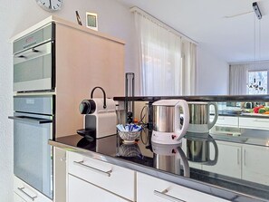 Eine moderne Küche mit Kaffeemaschine, Wasserkocher und Backofen.