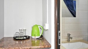Un baño con lavamanos, ducha y hervidor verde en la encimera.