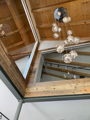 Ein modernes Interieur mit Holzbalken, einer Glasdecke und einer hängenden, kugelförmigen Leuchte.