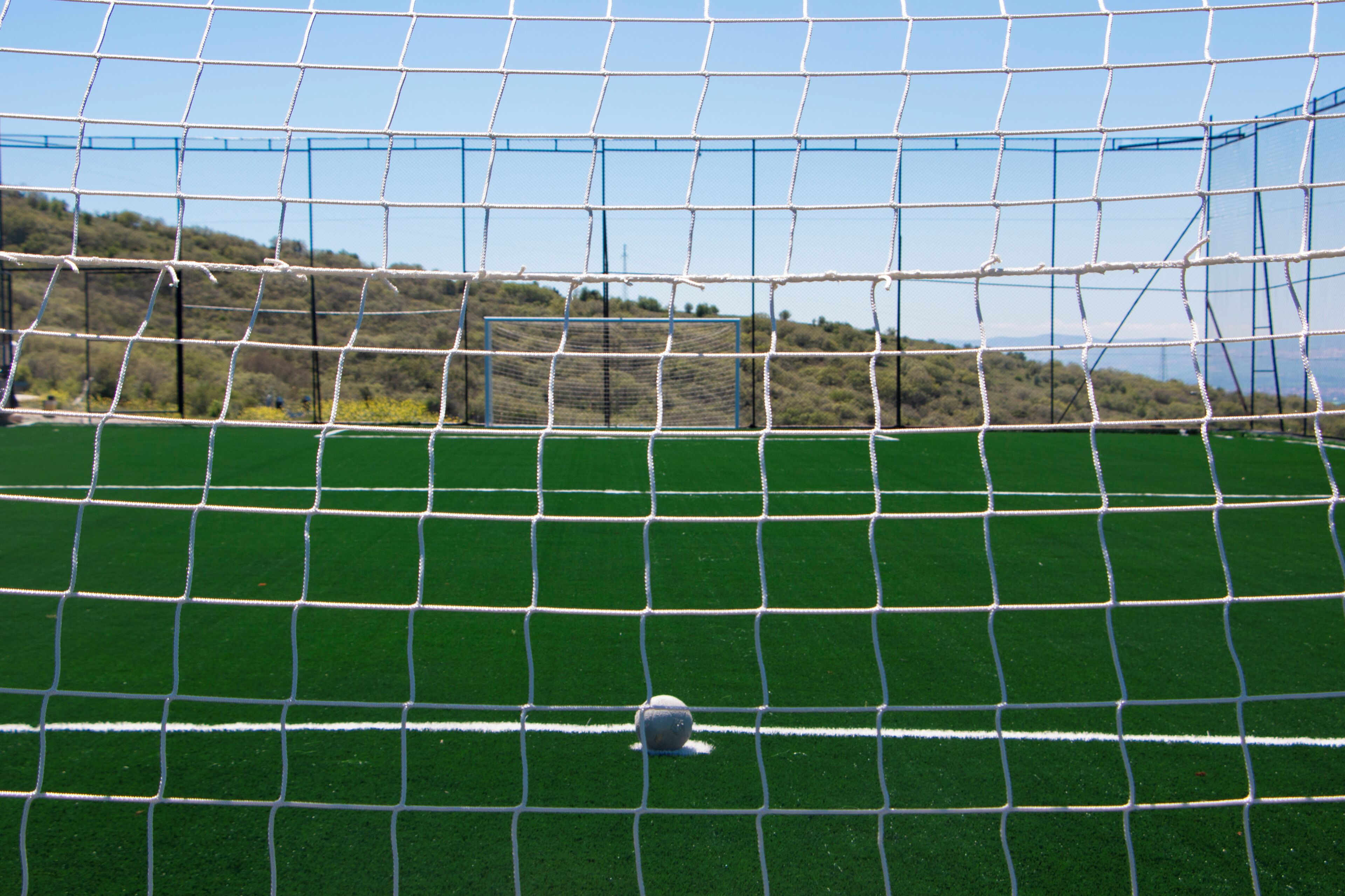 Un but de football avec un filet, entouré d’un terrain vert.