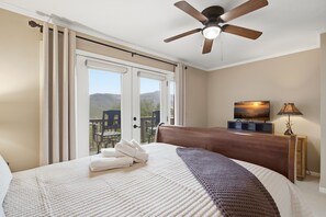 A hotel room with a bed, a ceiling fan, a television, and a view of the outdoors. - Kick App VIEWS! Mt Cabin w/Hot Tub +Fireplace (Seven Devils)