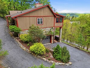 A two-story wooden house with a stone foundation, a garage, and a driveway. - Kick App VIEWS! Mt Cabin w/Hot Tub +Fireplace (Seven Devils)