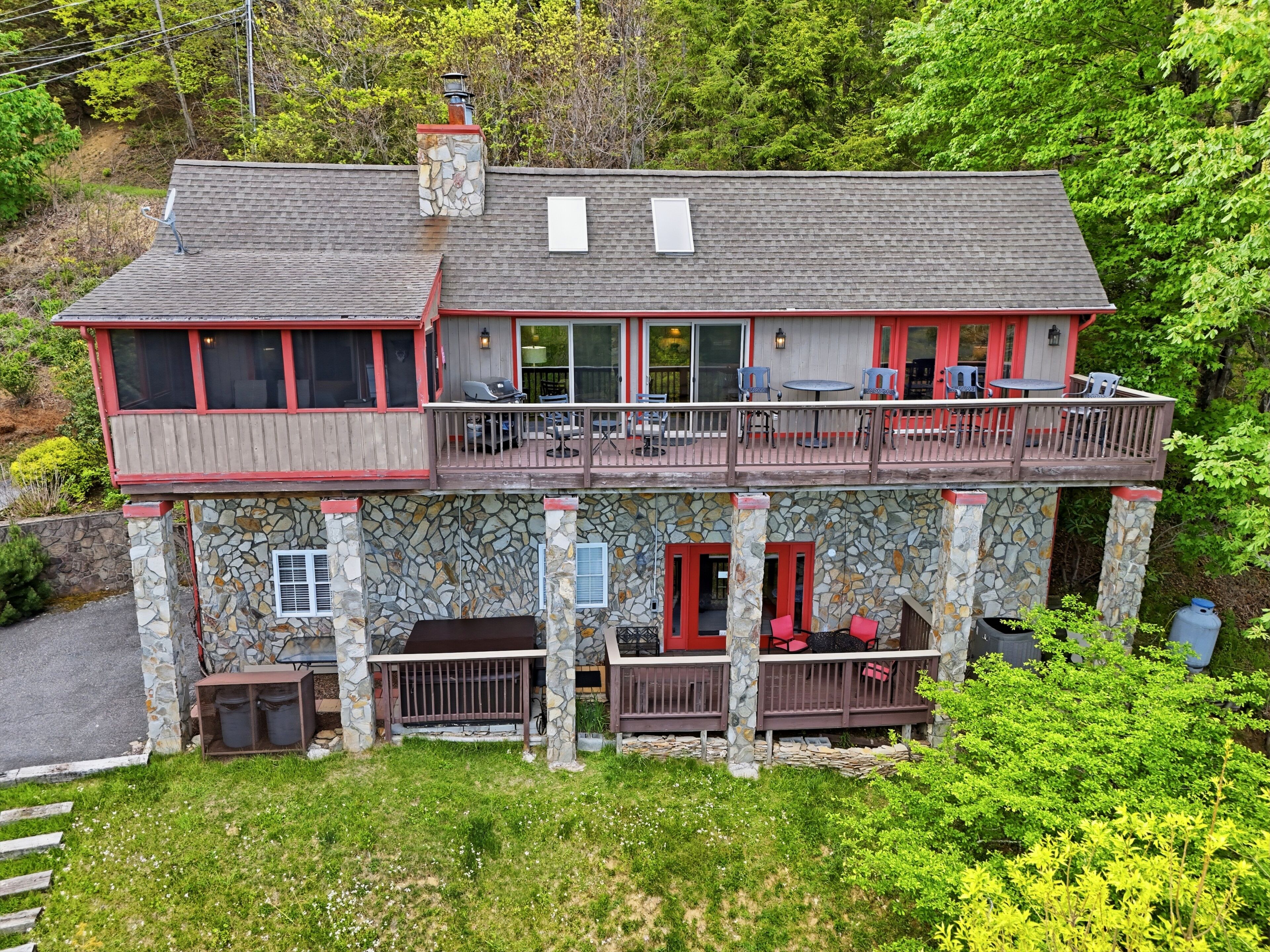 A two-story stone building with a balcony, outdoor seating, and a stone chimney.