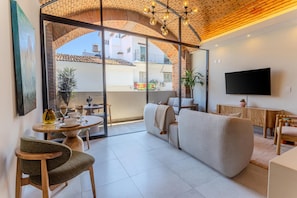 Ein modernes Wohnzimmer mit einer Couch, einem Fernseher und einem Essbereich mit Tisch und Stühlen.